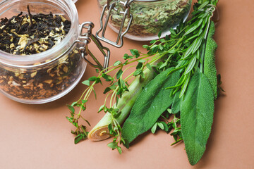 Different varieties traditional black, red and green tea glass jar and on a metal spoon on beige...