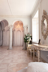 Luxurious light interior of the living room in the baroque style as in a royal castle with old stylish vintage furniture, columns, stucco on the walls
