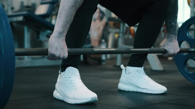 Strong man doing barbell snatch exercise at gym