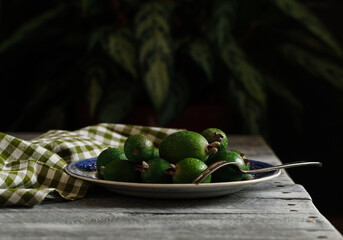 Fresh green feijoa fruits on a vintage plate on a wooden background. Rustic style