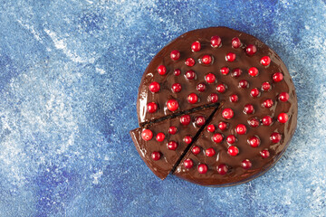 Gluten-free Brownie cake with chocolate icing, decorated with cranberries, on a blue background....
