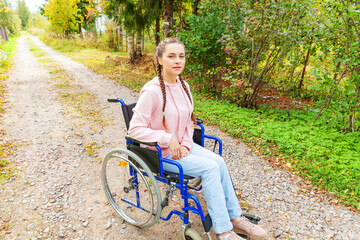 Young happy handicap woman in wheelchair on road in hospital park waiting for patient services....