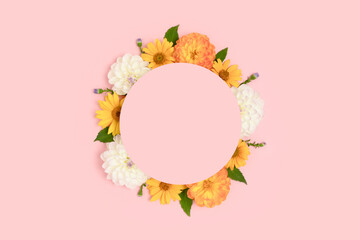 Wreath made of dahlia and arnica on a pink background. Flower round frame with copyspace.