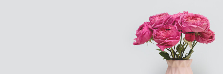 Banner with bouquet of rose flowers in front of blue background. Floral composition with copyspace.