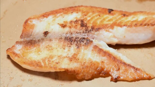 Tilapia fillet (Saint Peter) being finished in the frying pan (side tracking).
