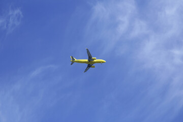 passenger yellow plane with landing gear down in blue sky with copy space for text and image