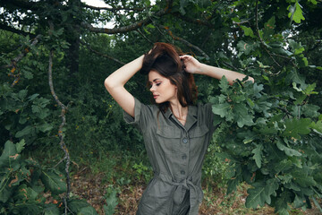 Woman in the forest A green jumpsuit looks towards green leaves background nature 