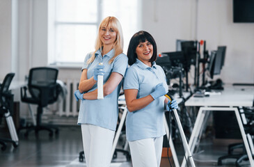 Fototapeta premium Group of workers clean modern office together at daytime