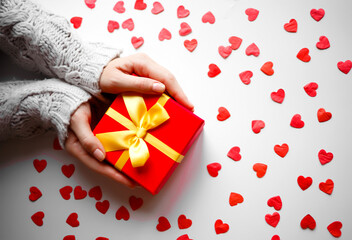 hands hold a gift on a white background with red hearts