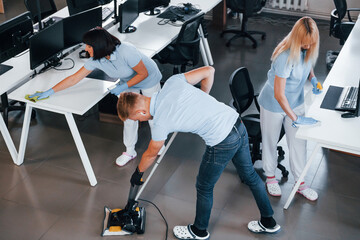 Fototapeta na wymiar Concentrated at job. Group of workers clean modern office together at daytime