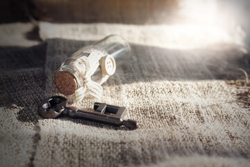 Ancient key and scroll message in the bottle with the white burlap background.Concept background for Valentine's day.