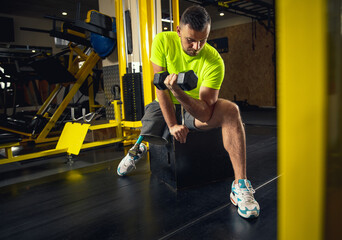 Weights. Disabled man training in the gym of rehabilitation center, practicing. Active man with...