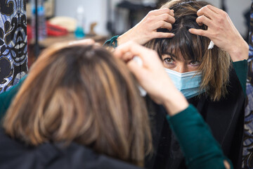 woman looking at hair in mirror