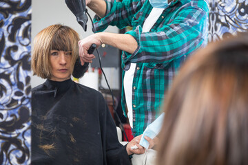 Fototapeta premium hairdresser stylist retouching hair to woman