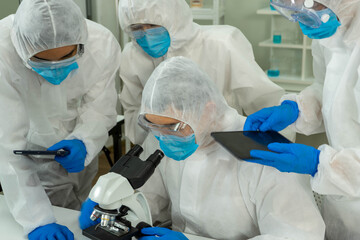 Group of four Asian medical scientists wearing PPE protective suits working with blood sample in laboratory.  Healthcare and medicine concept. virus pandemic concept. 