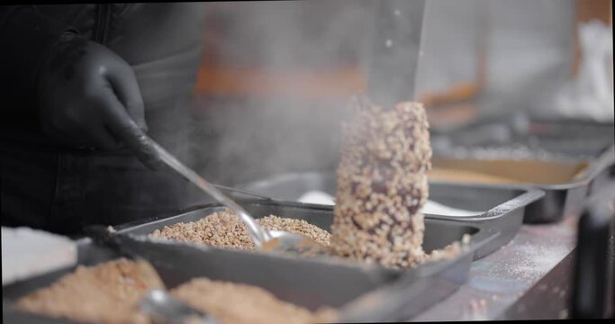 Preparing trdelnik a traditional chech street sweet food on a Christmas fair outdoors. Close-up video shot