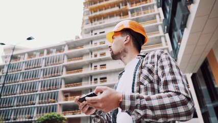 Architect working with smartphone on construction site. Engineer check construction plan on...