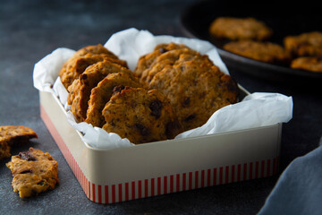 Oat cookies with chocolate chips and dried fruits, dark background.