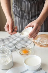 The process of preparing the dough at home. The woman adds the cream cheese to the bowl with the eggs. Vertical photo. Homemade food.