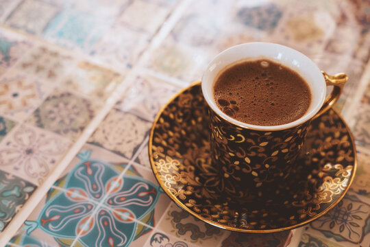 Close-up Turkish strong coffee cup on a blurred background oriental tiles. © dvulikaia