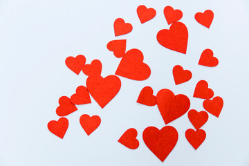 Red felt hearts of different sizes are on a blue background as a decoration or a design card.