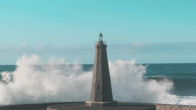 Slow motion strong waves crash against a lonely lighthouse in the open ocean