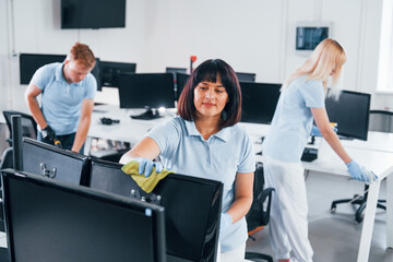 Group of workers clean modern office together at daytime