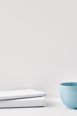 The mug stands on a stack of books on a white background. Natural and eco-friendly materials. Copy space, mock up