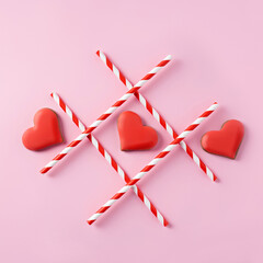 Tic-tac-toe with straws and red hearts on pink background. Love wins. Creative Valentines day or...
