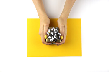 Small gift box with bow in women's hands.
