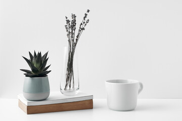 Mug and transparent vase with flowers on a white background. Eco-friendly materials in the decor of the room, minimalism. Copy space, mock up