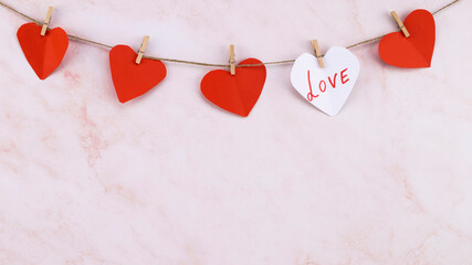  red heart shaped garland on over pink wall background. Valentine's Day garland