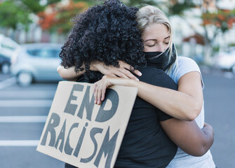 Young african woman hugging a caucasian woman after a protest - Northern woman with end racism...