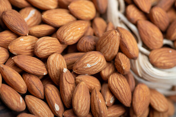 Almonds in a wicker basket and scattered on the table. Close-up, selective focus.