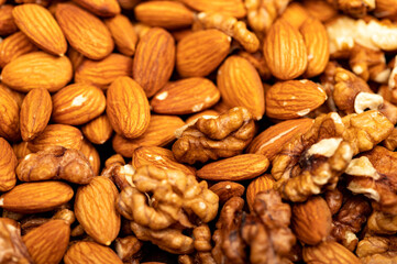 Almonds and walnuts scattered on the table. Close-up, selective focus.