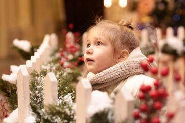  little blond baby girl in admire Christmas tree and decoration full body photo