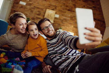 Cheerful family having fun while taking selfie with touchpad at home.