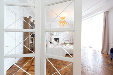 modern interior of a luxurious large bright two-room apartment. white walls, luxurious expensive furniture, parquet flooring and white interior doors