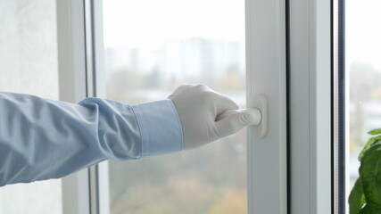 Hand with Protective Glove Opens a Window in a Hospital Room