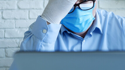 Doctor in a Hospital Office with a Face Mask and Protective Gloves Using a Laptop