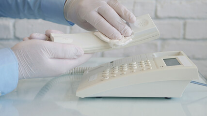 Image with Hands Wearing Protective Gloves Cleaning with a Clean Wipe and Medical Disinfectant a Telephone