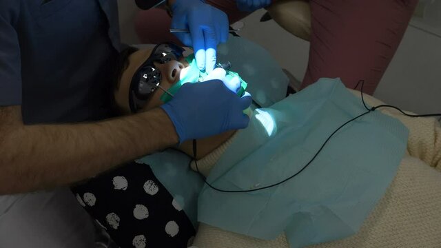 dentist treats deep caries pulpitis in a young man in a white sweater, checks the depth of the canal in the tooth