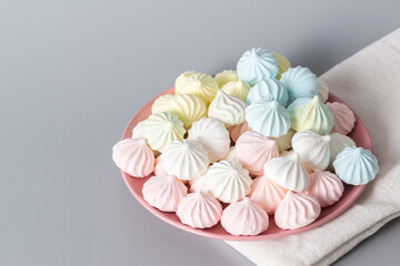 Sugar protein dessert in pastel colors in a pink plate on gray background. Linen napkin. Close-up