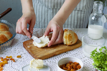 Female hand lubricates Easter buns with butter.