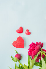 Valentines day composition with red peonies and red hearts on a light background