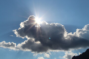 Sonne strahlt hinter dunklen Wolken hervor