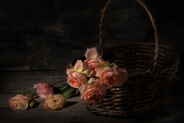 A bouquet of roses in a wicker basket on a wooden background.
