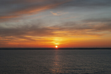 Beautiful cloudy sunset over the sea just as the sun touches the horizon.