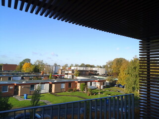 Blick vom überdachten Balkon einer Ferienwohnung auf eine Ferienhaus Siedlung bei Sonnenschein in...