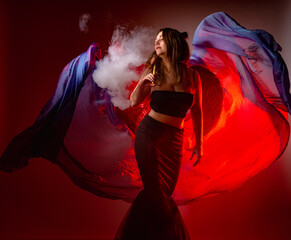 Girl with wings smokes a vape. Young girl with an electronic cigarette. Dancer holds vape device in...